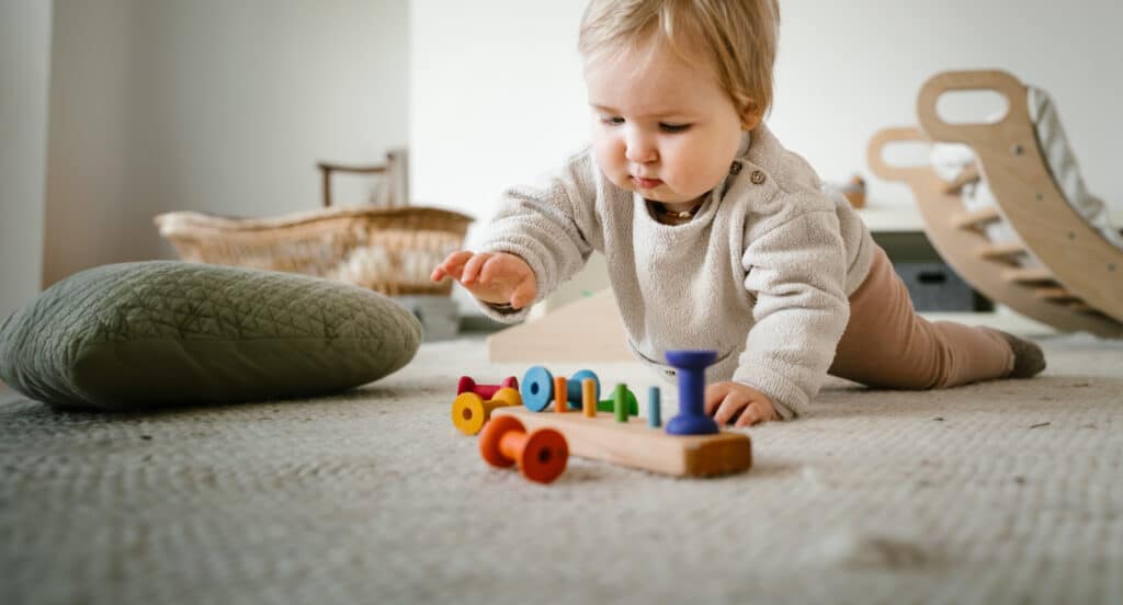 Kind spielt mit hochwertigen Spielmaterialien in Rosenheim in der schwerelos Familienbegleitung am Boden, fördert die Entwicklung gemäß den Prinzipien von Pichler und Montessori durch selbstbestimmtes, freies Spielen