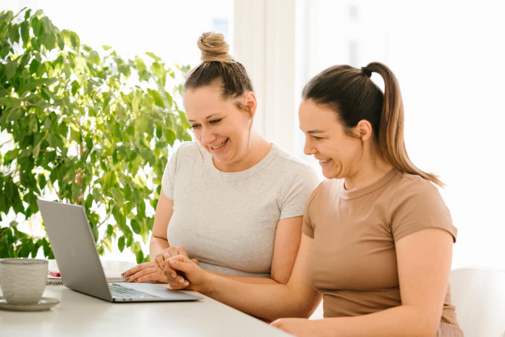 Sabrina Meister und Ramona Huber arbeiten am Schreibtisch und Laptop, um neuen Content für Eltern zu erstellen