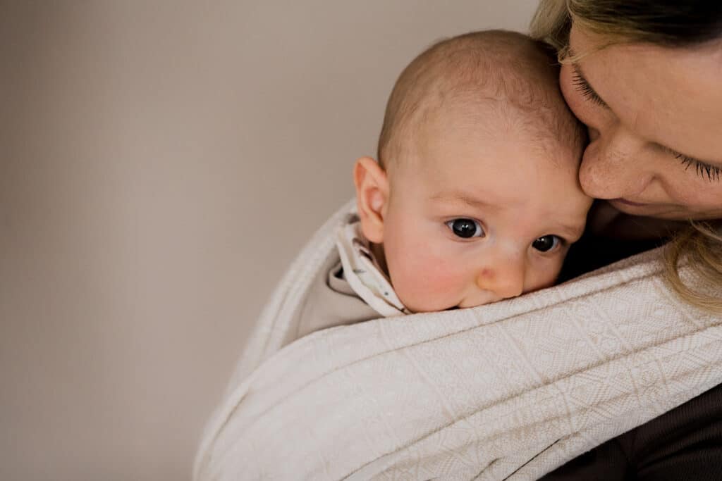 Baby, Säugling oder Kleinkind im Tragetuch, eng an die Mutter geschmiegt, fördert Nähe, Geborgenheit und die Mutter-Kind-Bindung