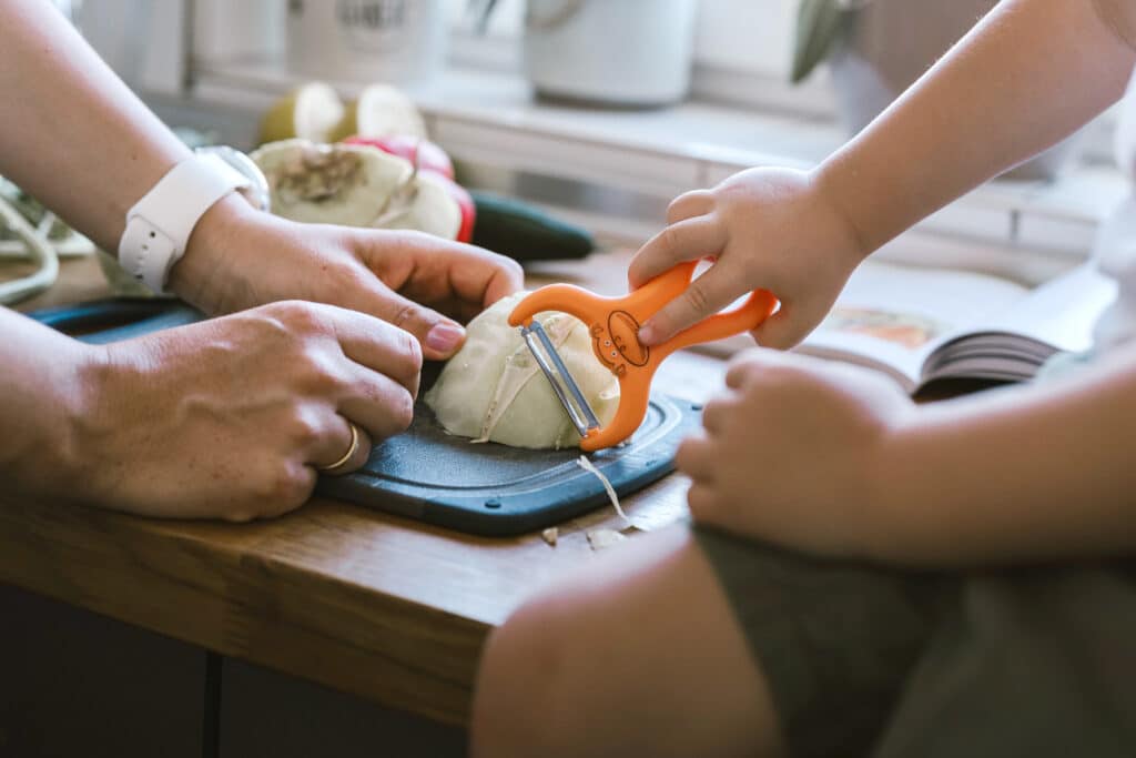 Kinder helfen in der Küche beim Kochen, entwickeln Selbstständigkeit und Feinmotorik gemäß dem Montessori-Ansatz.